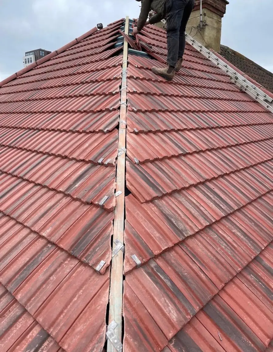 Red interlocking tile roof with the ridge being fixed, roofer on the slope