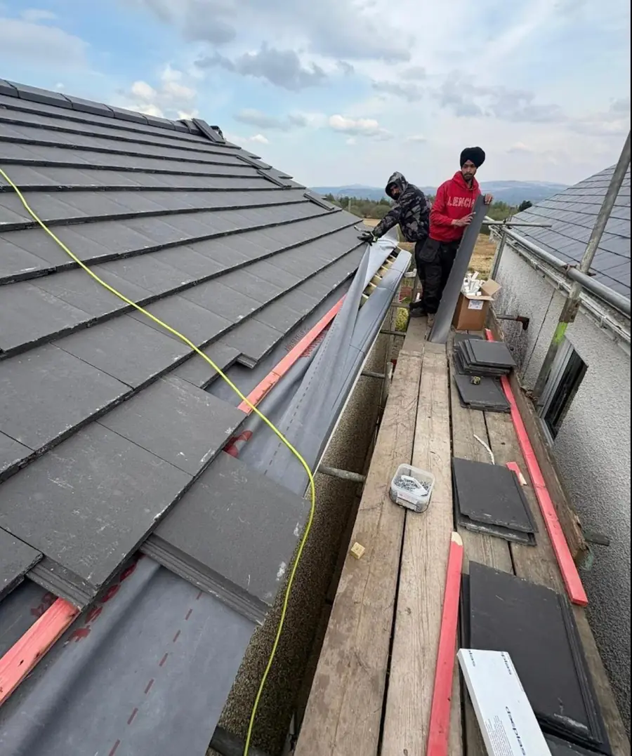 Two Best Top roofers laying slate-effect tiles and a lead valley from the scaffold